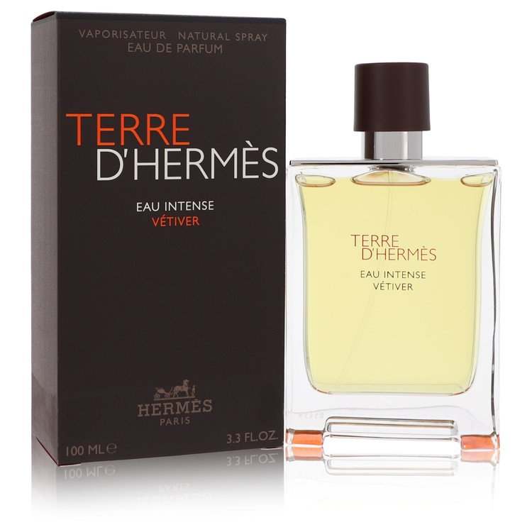 Eau de parfum spray in a clear glass bottle with pale golden liquid and dark brown cap, beside black box; Hermès Terre d’Hermès label.